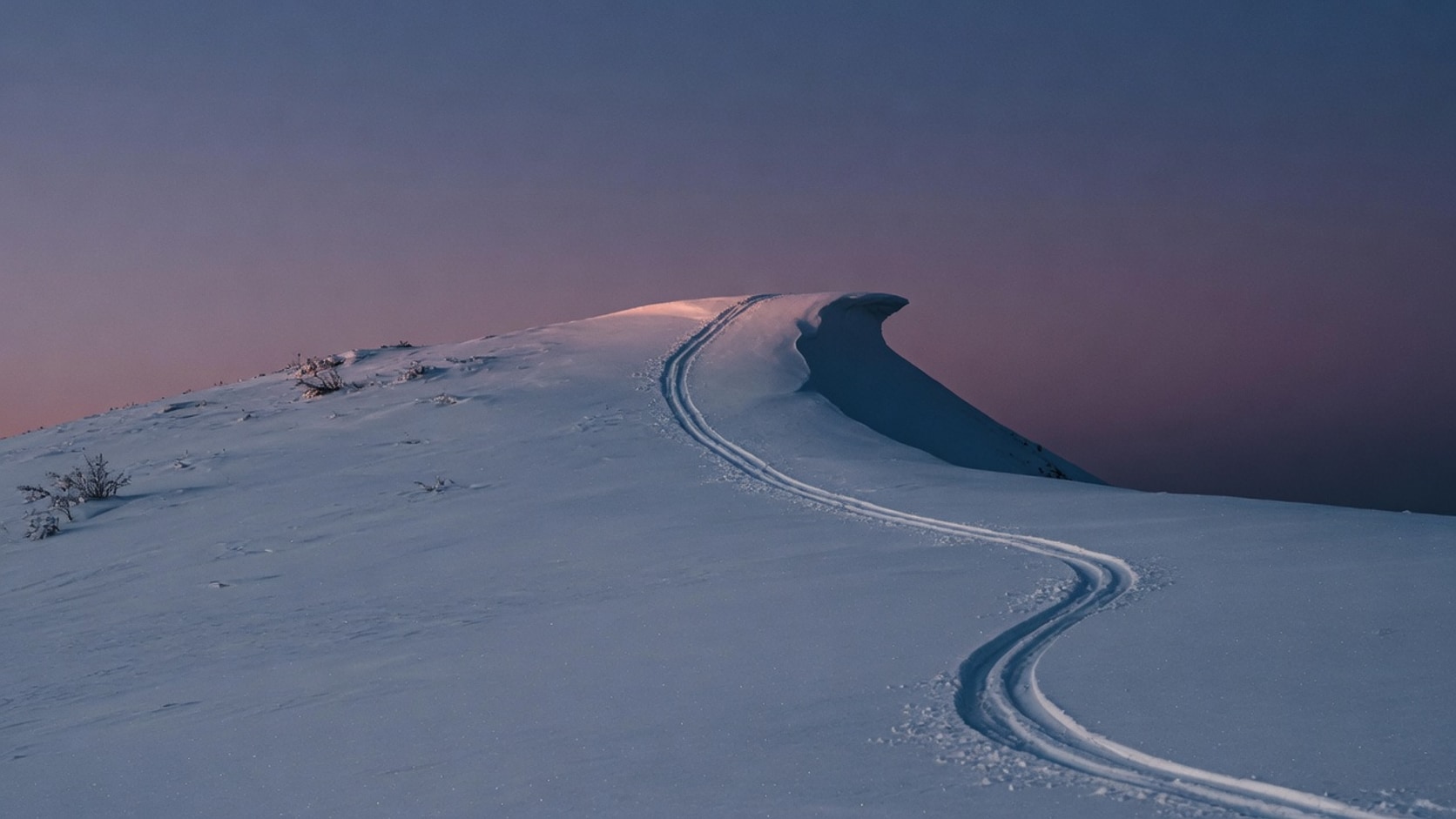 AI editorial photograph of a quiet snowy ridge at dusk with a single set of tracks ending at a jump